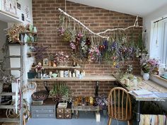 a room filled with lots of flowers and plants on shelves next to a brick wall