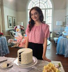 a woman standing next to a table with a cake on it