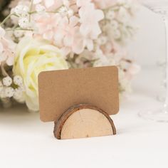 there is a piece of wood on the table next to some flowers and wine glasses