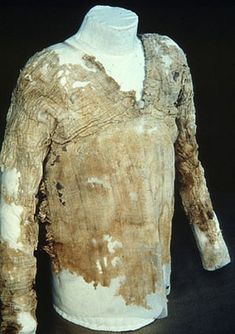 an old, worn out shirt is displayed on a black surface with white and brown paint