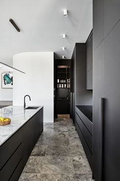 a modern kitchen with black cabinets and marble counter tops, along with an island in the middle