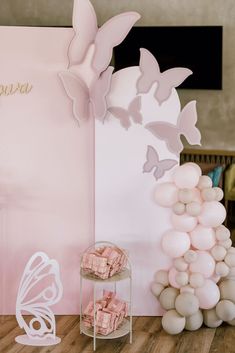 there is a pink and white backdrop with butterflies on it, along with balloons in the shape of flowers