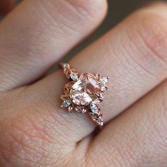 a close up of a person's hand wearing a ring with an oval shaped diamond