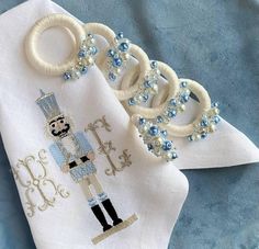 a blue and white napkin with an embroidered nutcracker on it, next to some beads