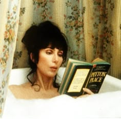 a woman laying in a bathtub reading a book