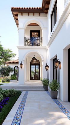 a large white house with blue and red tile on the front walkway, potted plants and trees