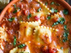 a bowl filled with pasta and sauce on top of a table next to a piece of bread