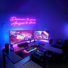 two computer monitors sitting next to each other on top of a desk in front of blue lights