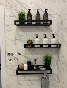 two shelves with soaps, candles and plants on them in front of a marble wall