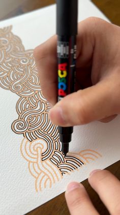 a person holding a marker in their left hand and drawing on paper with the other hand