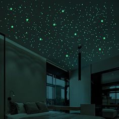 a bed room with a large bed and stars on the wall above it in green glow