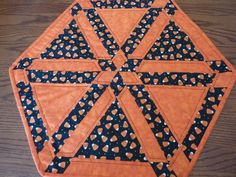 an orange and black quilted table topper on a wooden surface with polka dots