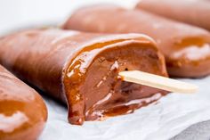 three hotdogs with ketchup on a stick in front of some donuts