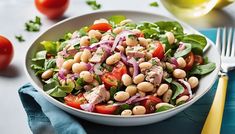 a white bowl filled with salad on top of a blue cloth next to a fork