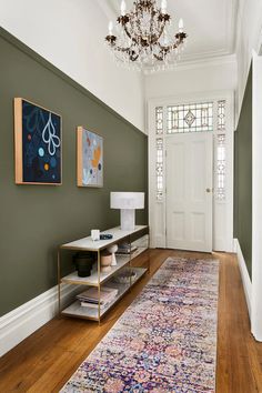 a hallway with green walls and a rug on the floor next to a white door