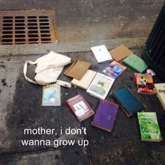 there are many books left on the ground next to a trash can and drain grate