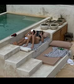 two women lounging on loungers next to a swimming pool