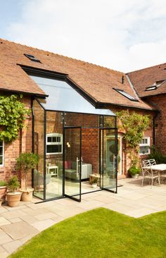 a brick building with glass doors and windows on the outside, surrounded by greenery