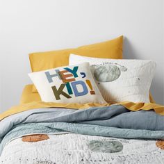 a bed with yellow sheets and pillows on top of it next to a white wall