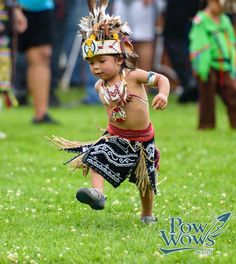 a little boy dressed in native american clothing and headdress running through the grass