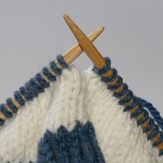 a close up of a crocheted blanket with two knitting needles sticking out of it