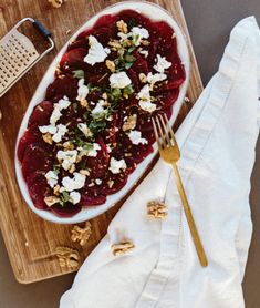 a bowl of food on top of a cutting board next to a fork and napkin