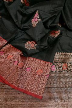 This latest collection is in a black and red color combination, a pure tussar silk banarasi saree with golden zari and meenakari work, and in an alluring meenar butta work on the body and traditional meenakari work on the pallu and the border and all over. Color: A shade of black and red color Technique: A pure and refined hand-done work of border with meenakari zari work and traditional meena butta work Fabric: Tussar Quality: IndyVogue's Assurance of Silk Mark Certification Note: Comes with co