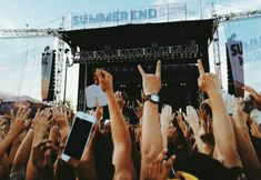 many people are holding their cell phones up in the air at an outdoor music festival