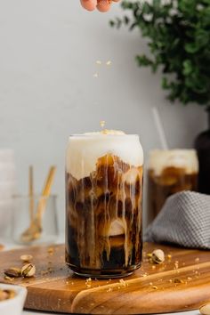 someone is sprinkling some food into a drink in a glass on a cutting board