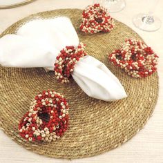 the table is decorated with red and white beaded napkins on top of straw