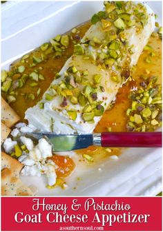 a white plate topped with cheese and nuts next to crackers on top of a table