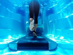 a person is walking up the stairs in an aquarium with blue water and ice formations