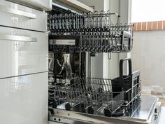 an open dishwasher in a kitchen with stainless steel cabinets and white cupboards