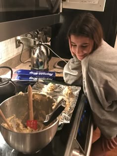 a woman is making food in the kitchen on the stove top with a large metal pan