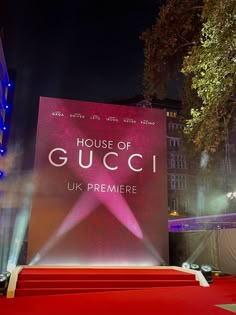 a red carpeted stage with the words house of gucci on it at night