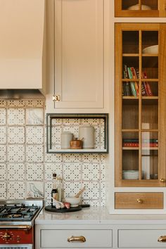 a stove top oven sitting inside of a kitchen next to a wooden cabinet filled with dishes