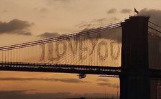 an airplane flying over the top of a bridge with writing on it's side