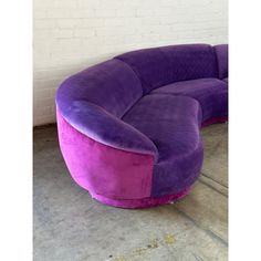 a large purple couch sitting on top of a cement floor