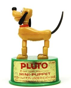 a dog figurine sitting on top of a green tin can with an advertisement for pluto