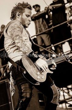 a man playing an electric guitar in front of a group of people on the stage