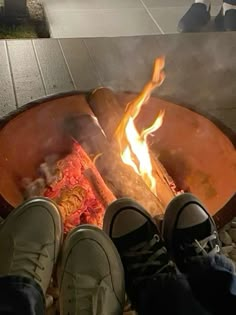 someone standing in front of a fire pit with their feet up on the ground next to it