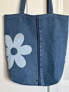 a denim bag with a flower painted on it hanging from a door handle in front of a white door