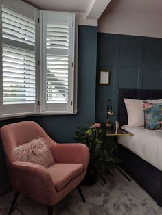 a bed room with a neatly made bed and a chair next to a large window