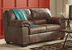 a living room with a brown couch and rugs on the floor in front of red walls