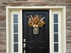 a black front door with an autumn wreath on it