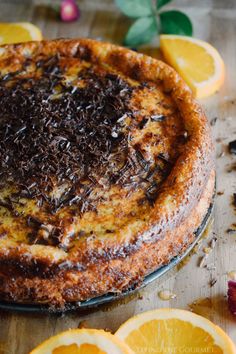 an orange and chocolate cake on a wooden table with slices of oranges around it