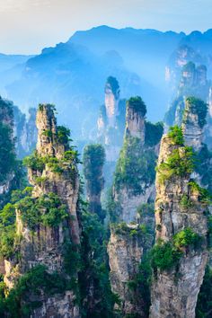 the mountains are surrounded by trees and rocks with green leaves on them, in china