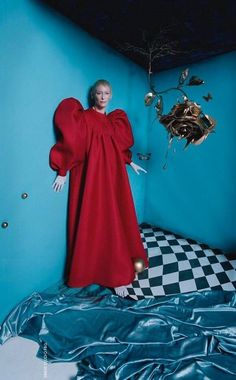 a mannequin in a red dress standing next to a blue wall