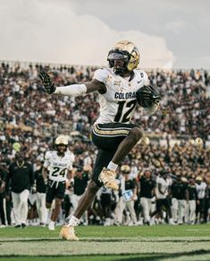 a football player running on the field with his arms out and feet in the air