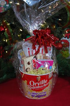 a basket filled with popcorn and candy next to a christmas tree